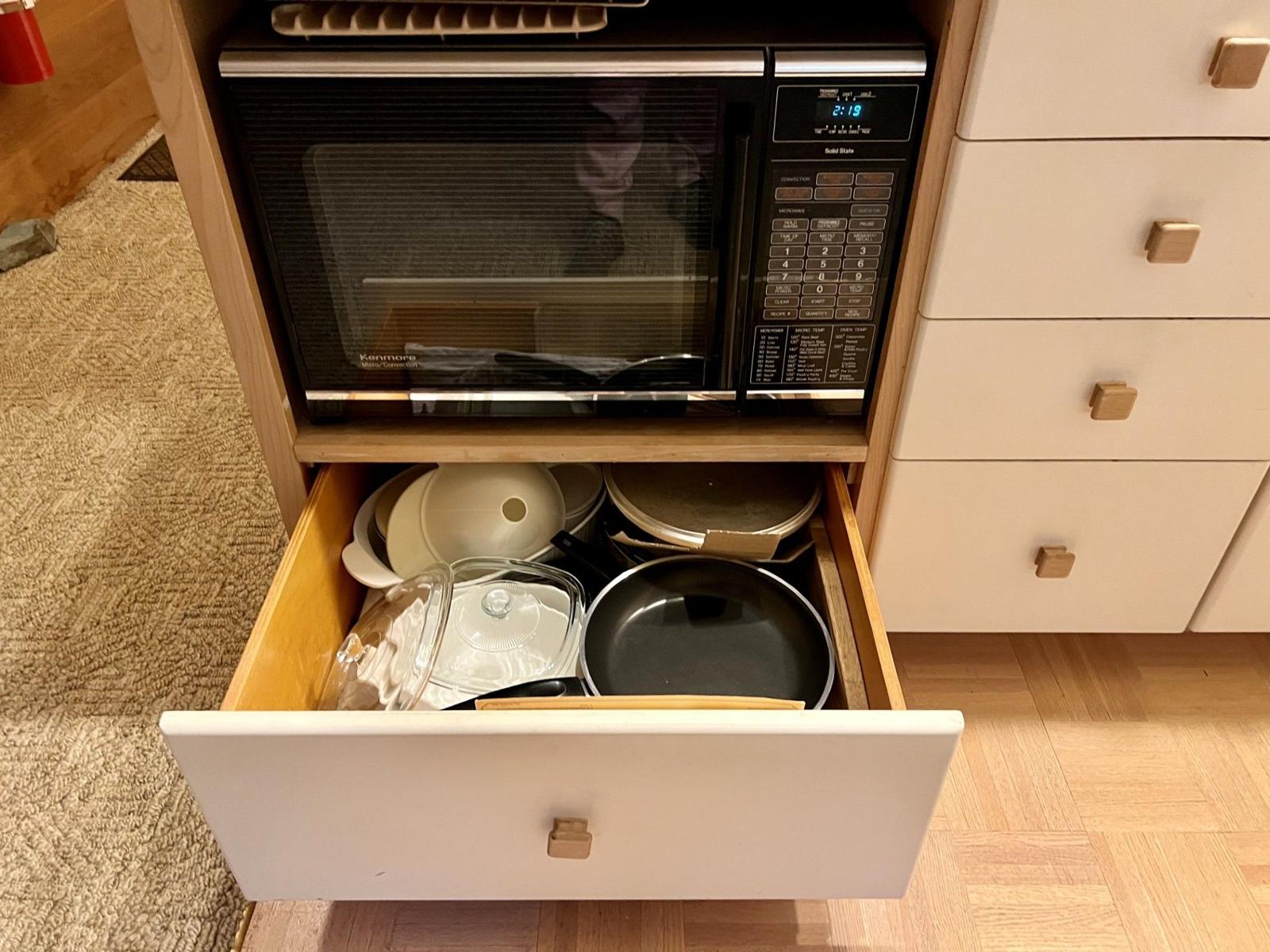 Microwave and a drawer of pots and pans