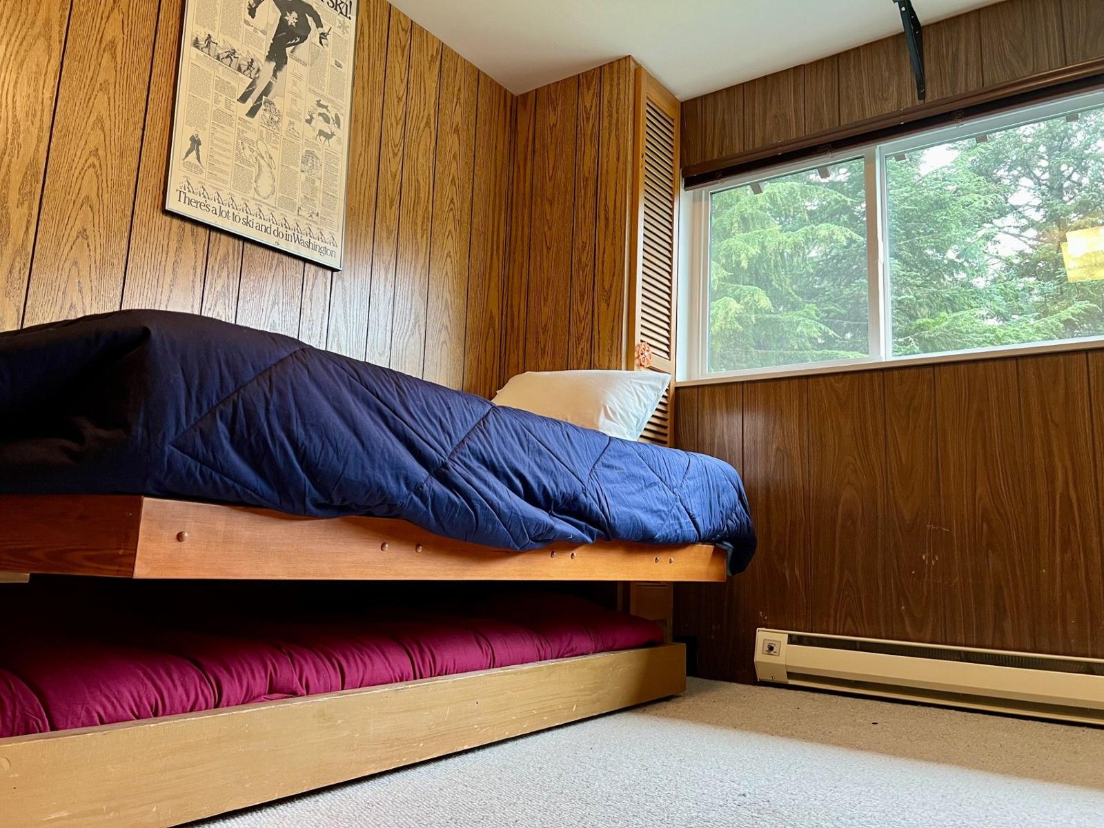 Bed by a window with a vintage ski poster