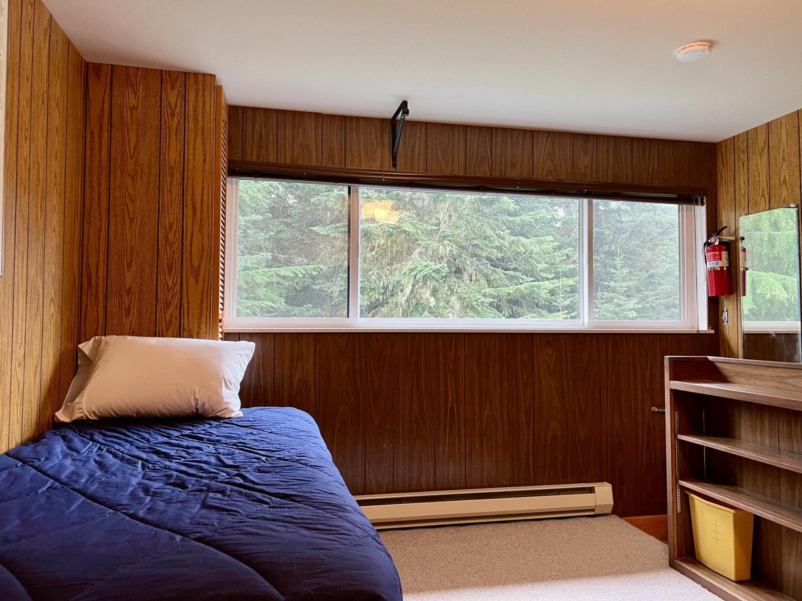 Loft bed beside a window into the forest